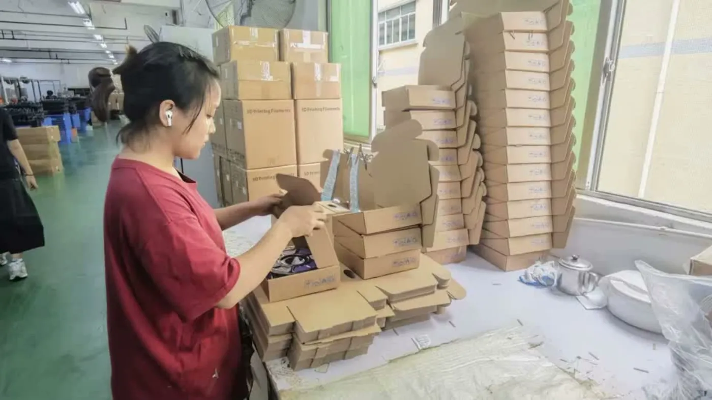Worker packing filament export cartons at the assessed manufacturing partner