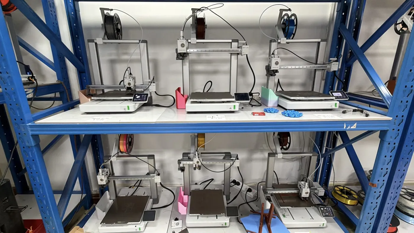 Rows of 3D printers on shelving in a print farm