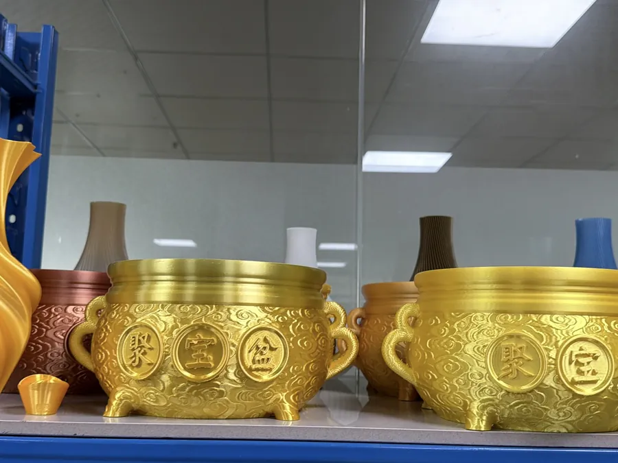 High-sheen gold 3D printed vessels and bowls on a shelf