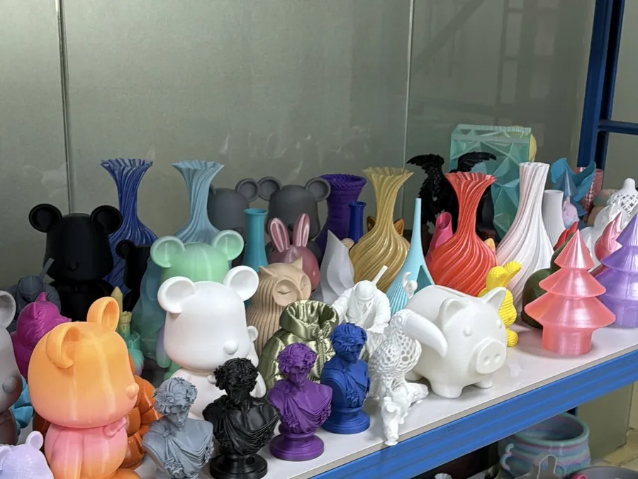 Assorted colorful 3D printed vases, figurines and busts on a display shelf